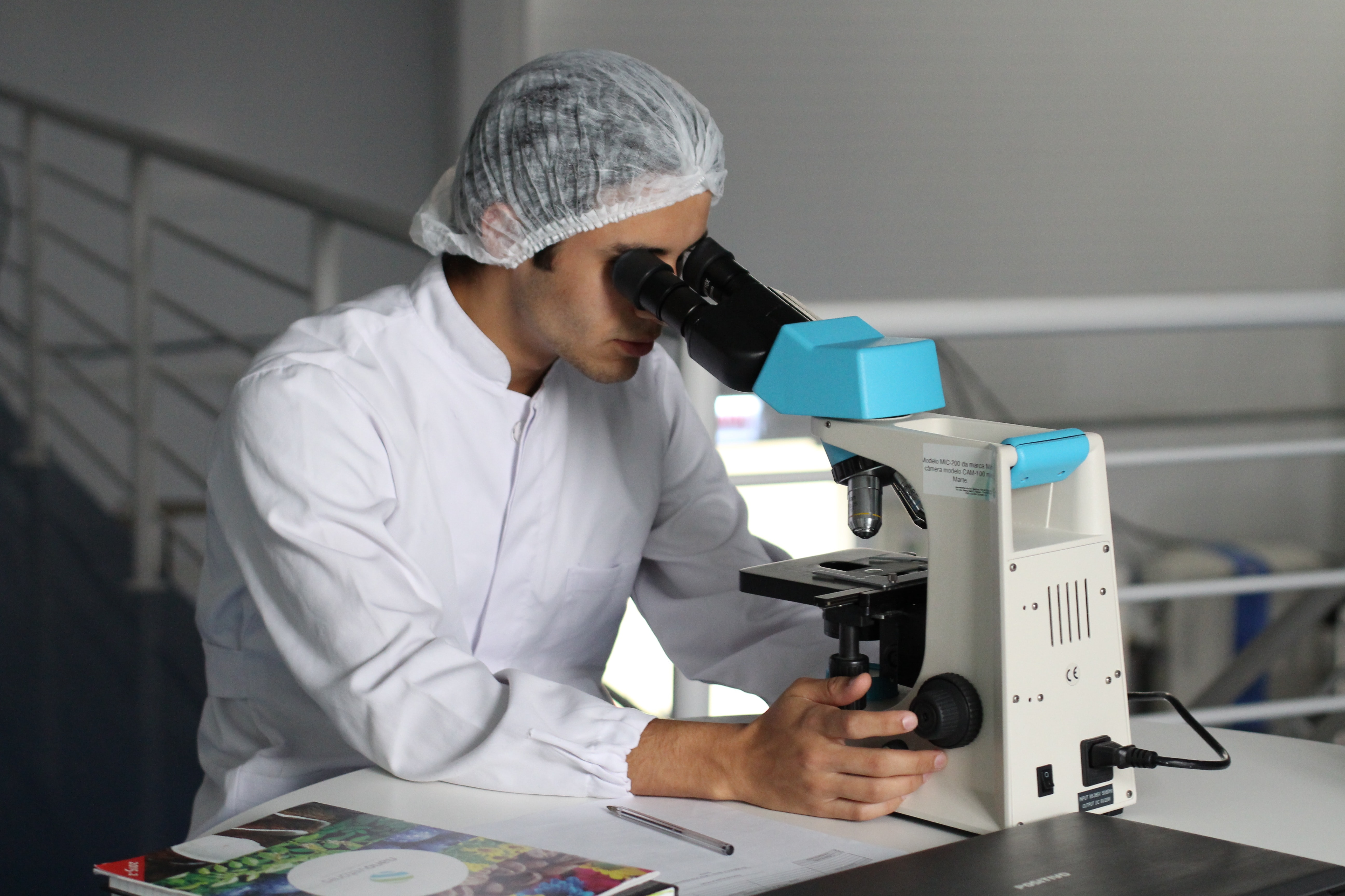 a man in light protective gear looks into a microscope