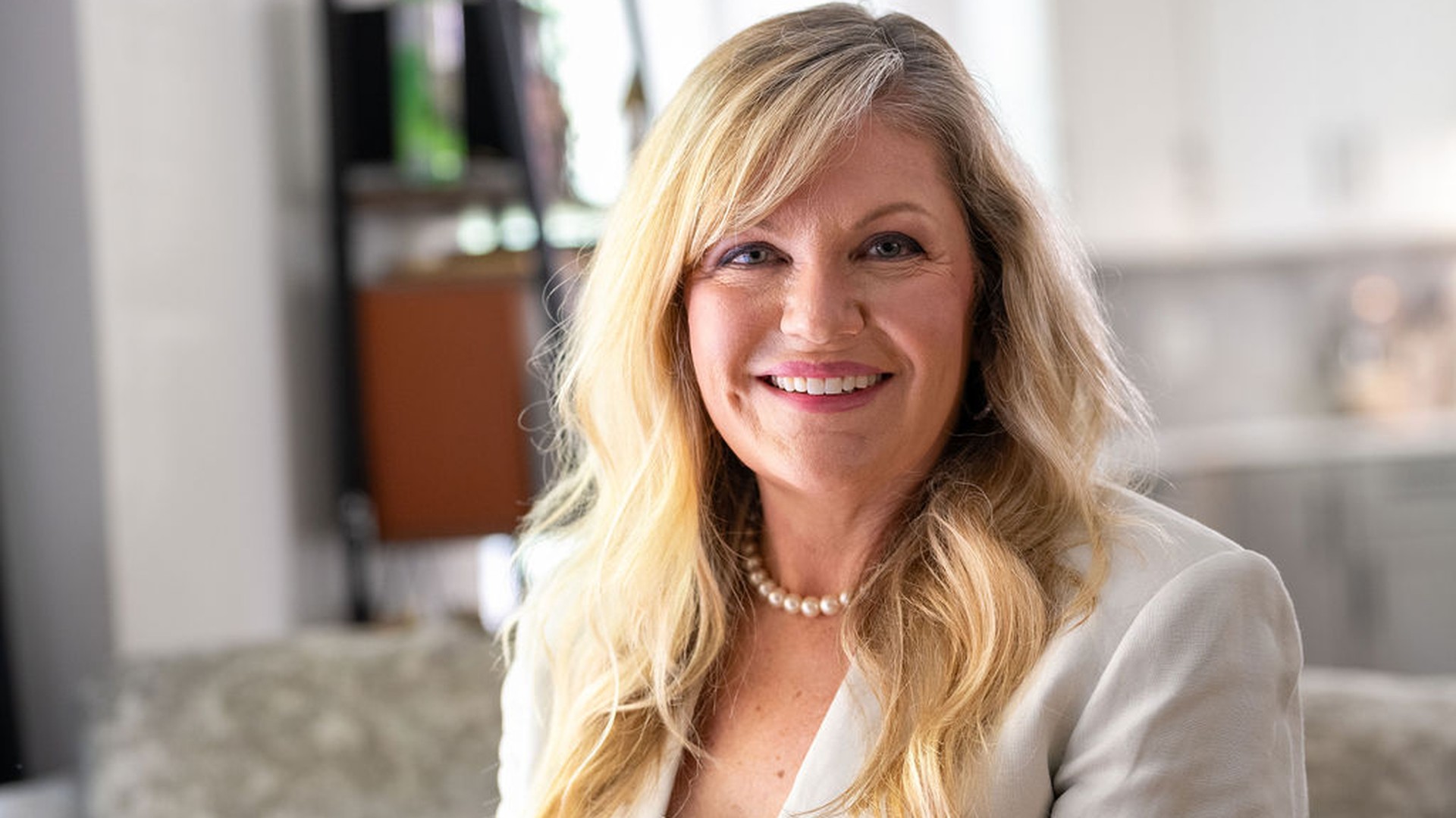 Woman in tan blazer sitting on couch