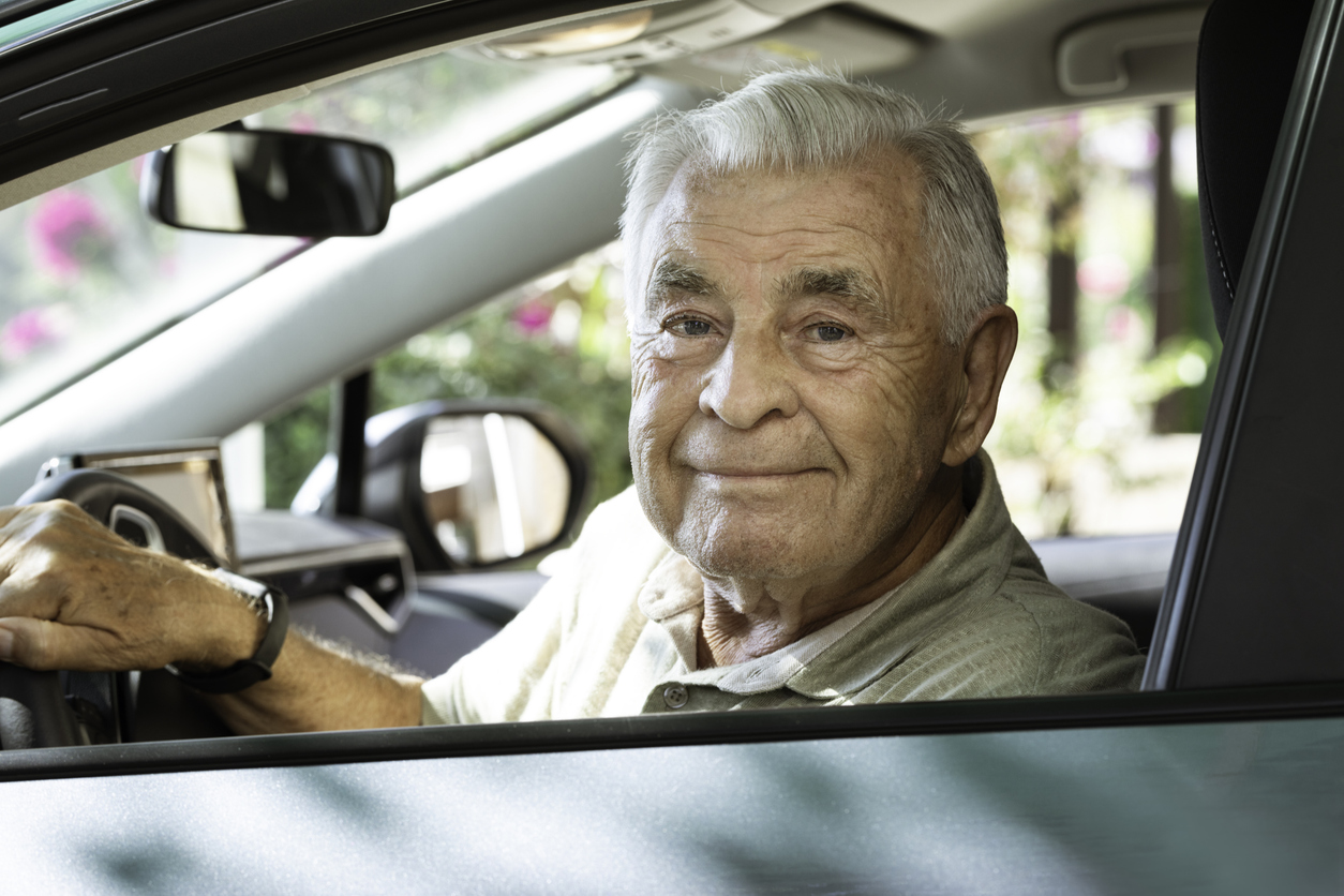 Senior in car is looking at camera with a warm smile.