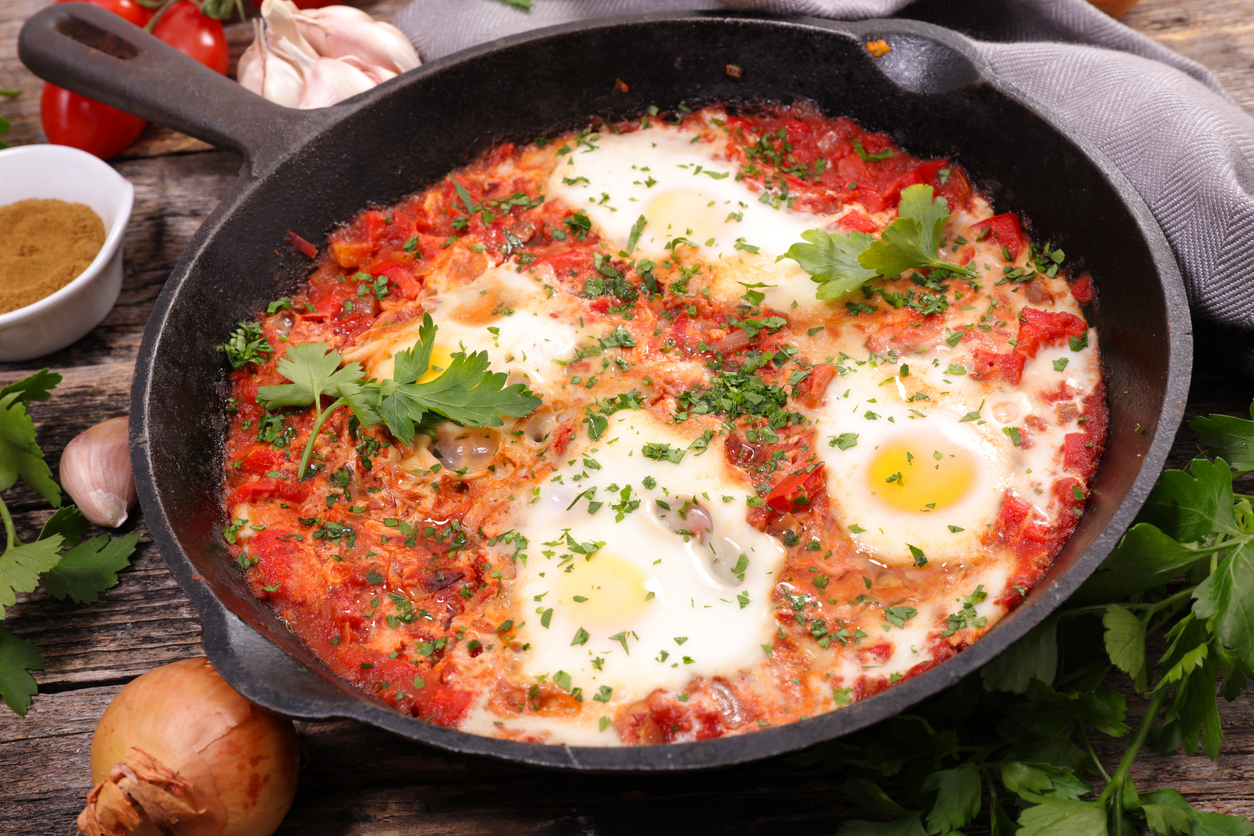 Baked egg with tomato in a skillet pan.