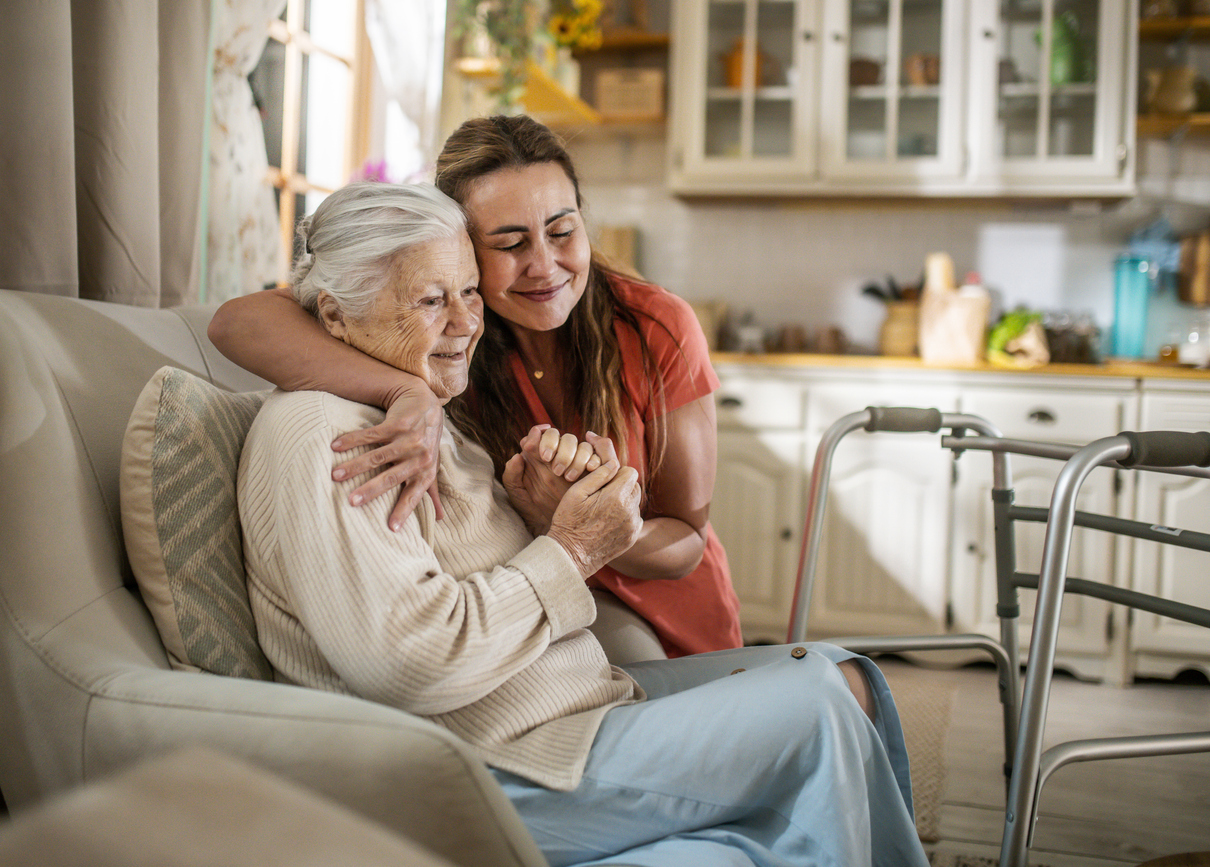 Daughter assisting senior woman with walker at home.