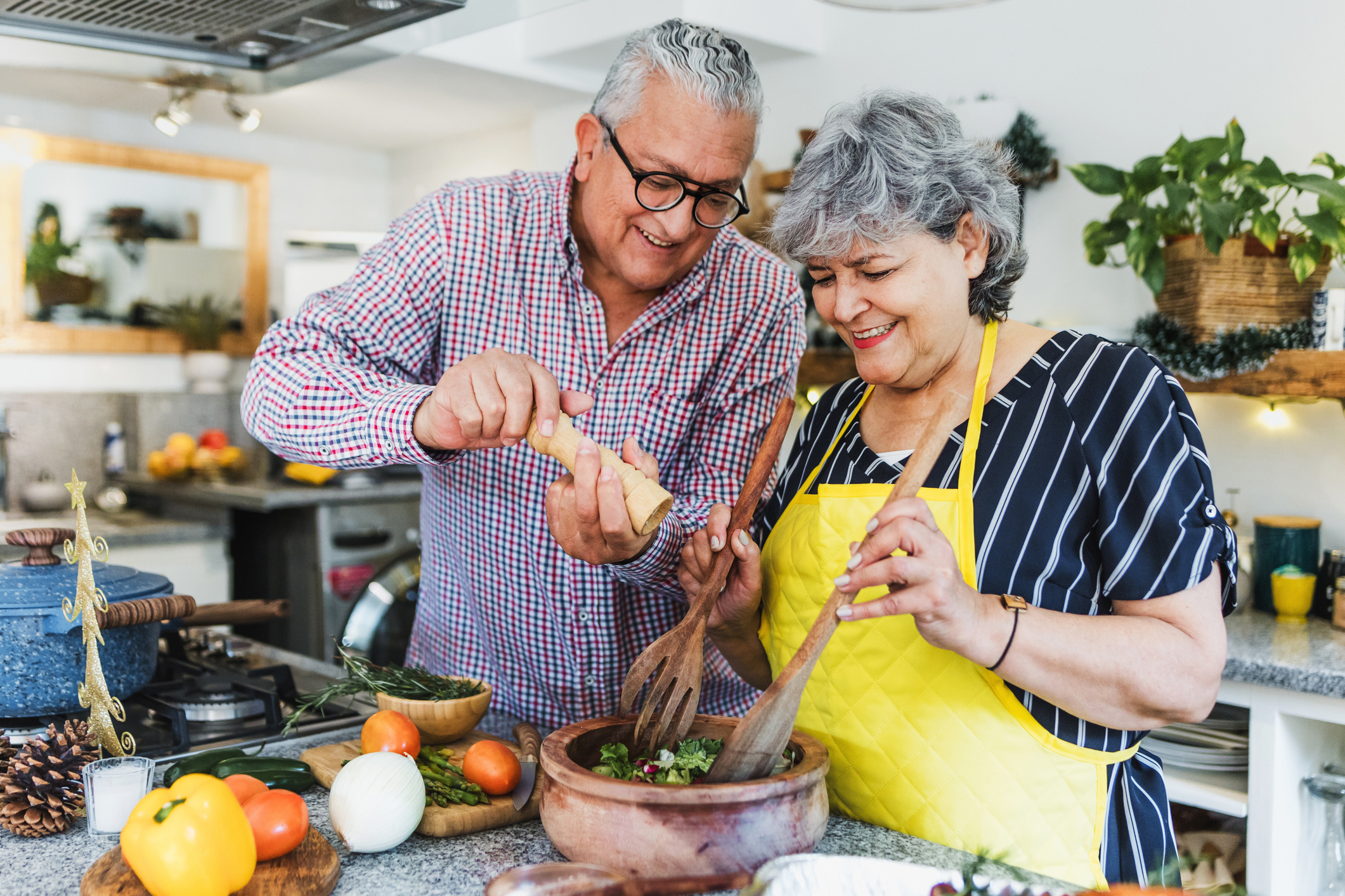 Latin senior couple cooking dinner at home.