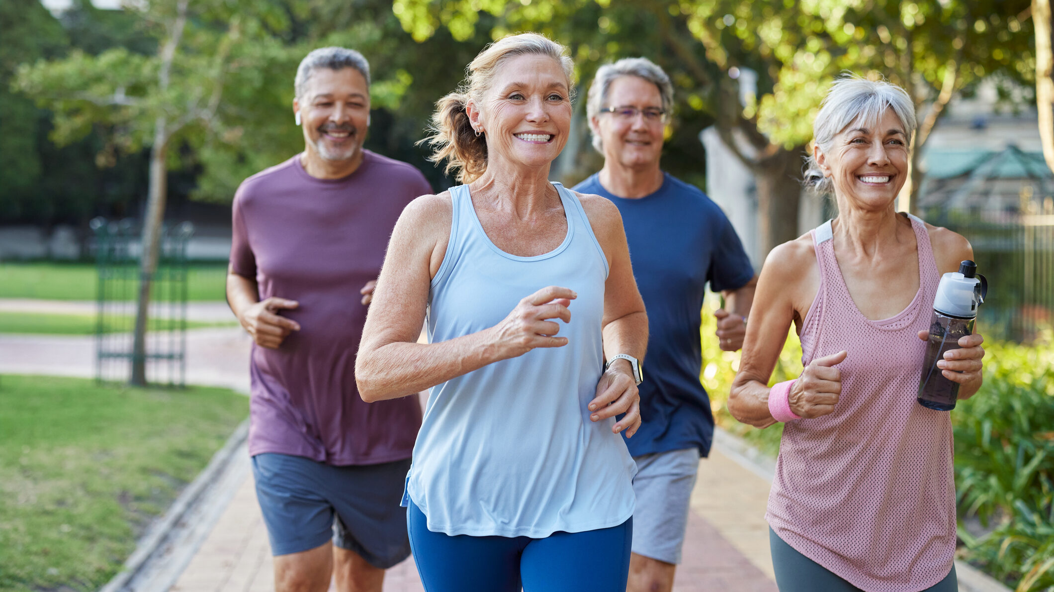 Group of happy older friends jogging in a city park.