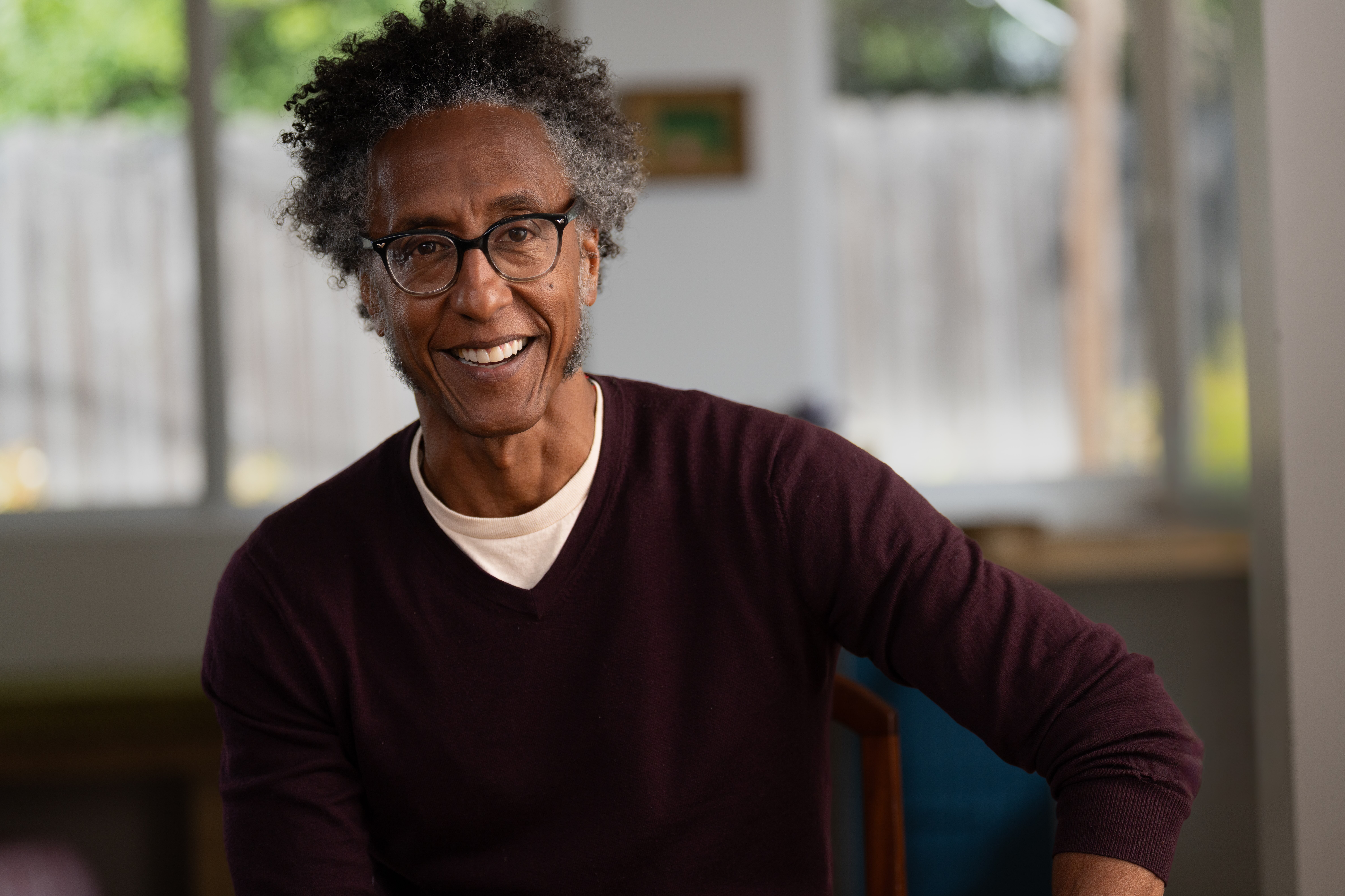 Andre Royo sitting down indoors smiling.