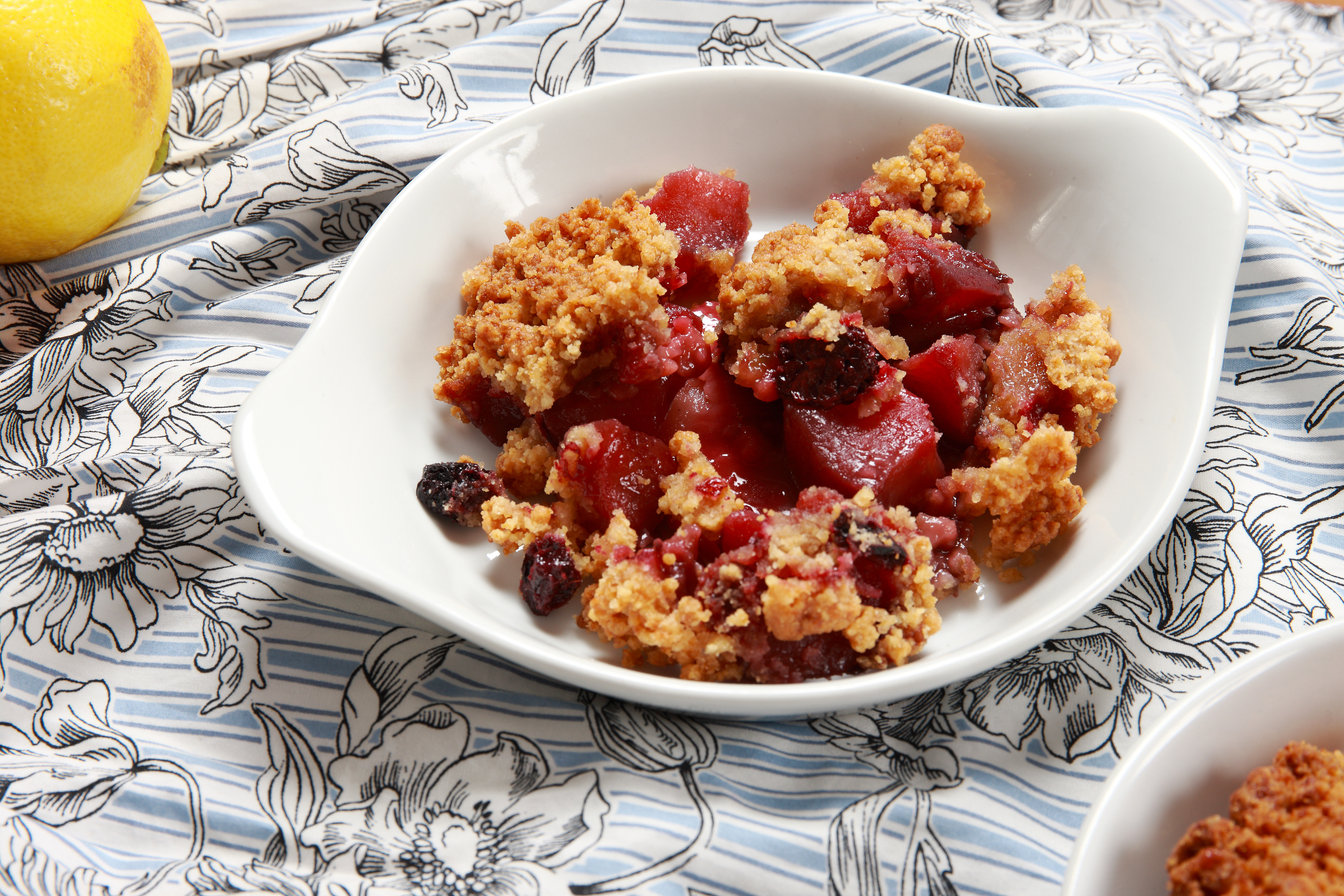 White plate with pear chunks and cranberries topped with a crumble